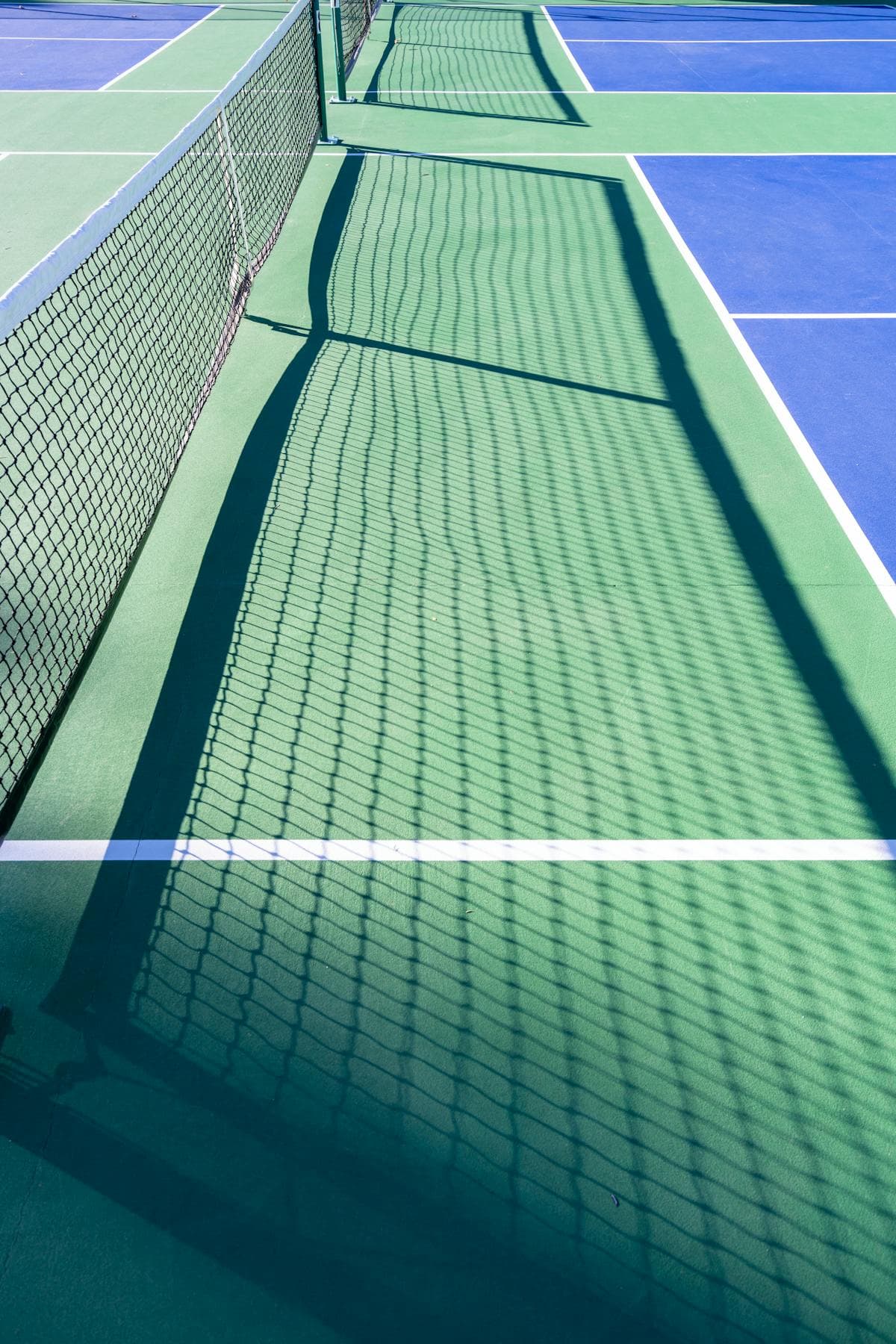 Net shadow on sunny outdoor pickleball court